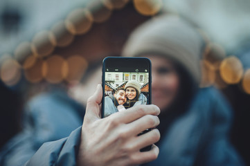 Young beautiful cheerful couple taking a selfie in the city stre 