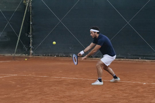 Young man playing tennis on a clay court