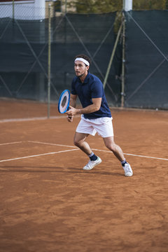 Young man playing tennis on a clay court