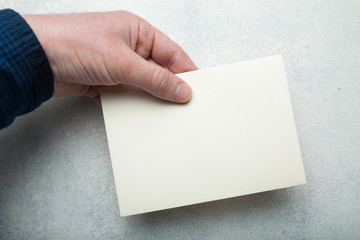 Beige pastel envelope for mail on a background of a light vintage table in hand. Template, mock-up.