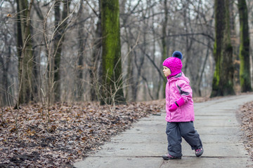 Fototapeta premium Little girl walking alone in a forest at autumn