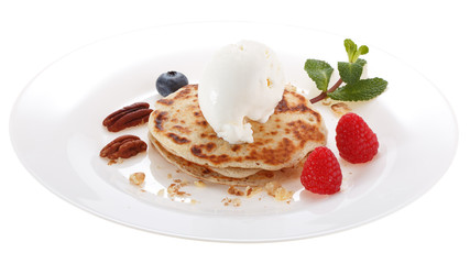 Serving pancakes with ice cream on the plate. Decorated with nuts, fresh berries and mint. Isolated on white background.
