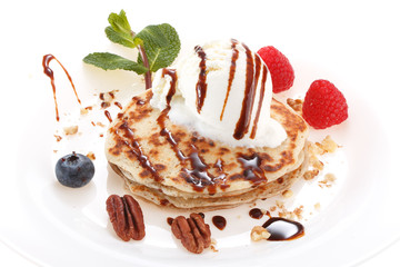 Serving pancakes with ice cream on the plate. Decorated with chocolate syrup, nuts and fresh...