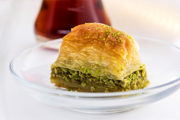 Baklava with pistachio and turkish cup of tea on a white background