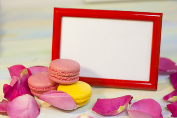 The concept of Love, Wedding, Proposal, Anniversary, St. Valentine's Day with a red photo frame, colorful macaroons and pink rose petals, light background