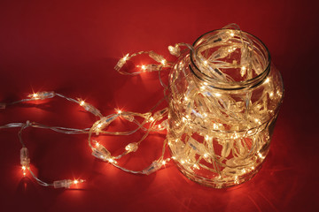 Christmas lights in a jar on a red background.