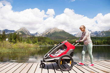 Senior woman and children in jogging stroller, summer day.