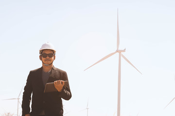 Portrait of business asian man holding tablet with the wind turbine in background.