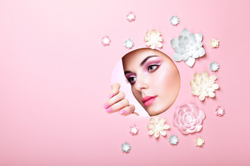 Conceptual Beauty Portrait of Beautiful Young Woman. Face of Girl with Spring Pink Make-up. Beauty Fashion Model Woman Face perfect Skin. Paper Flowers on Pink Background