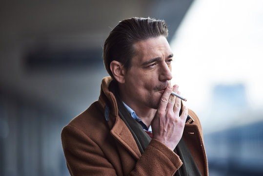 Portrait of pensive male smoking while situating outside. Smoke concept