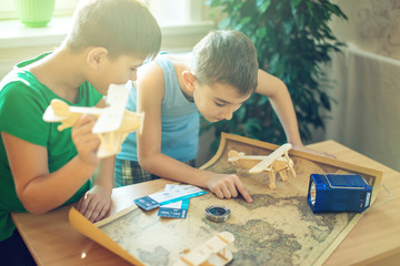 Happy children boys with airplane in hand, explore the map below to travel to new adventures.