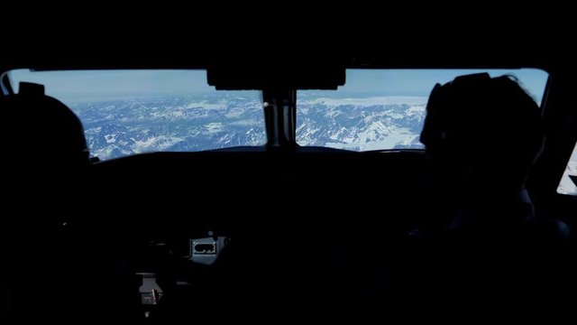 Looking out pilot cockpit window, flying over snowy mountains, Greenland.