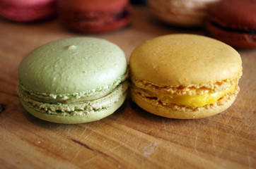 macaroon dessert with colored fillings lie on a wooden table