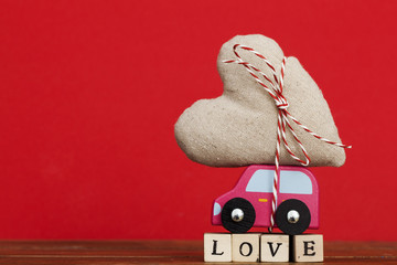 Wodden toy car carrying a love heart. Valentines day, mothers day concept