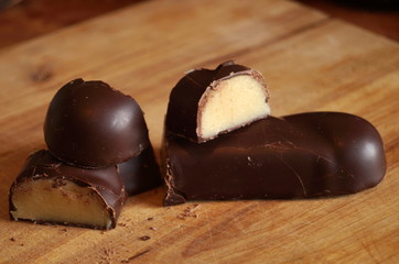 Candy with a marzipan covered with chocolate on a wooden table