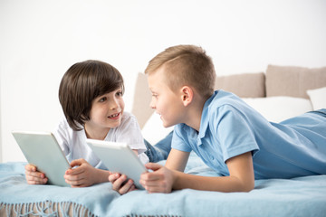 Two kids discussing new game with enthusiasm while playing the tablet at home