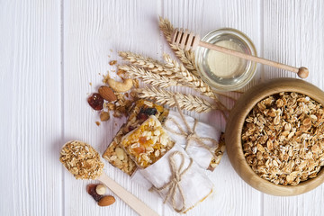A wooden bowl of dried fruit, raisins, cranberry with almonds, raisins, seeds, cashew, hazelnut nuts mix on white table. Sporty fitness energy bar snacks vegan style. Close up, top view, copy space.