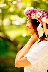 Portrait of young woman with wreath of fresh flowers on head