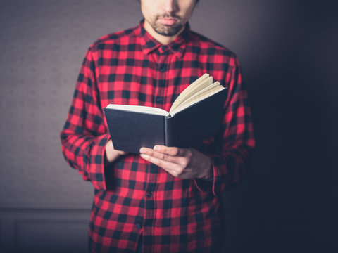 Man in red flannel shirt reading a book