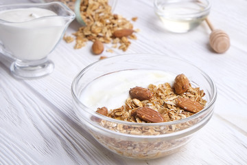 Glass bowl with Greek yogurt and mixed nuts. Healthy sports vegetarian protein rich diet, homemade granola breakfast with milk, honey, almond, cashew, hazelnut, rolled oats. Top front view, background