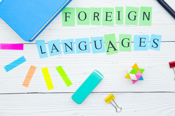 Education concept: Foreign Languages inscription and bright school supplies on a white wooden background, close up, top view