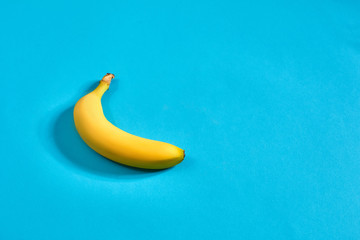 Yellow ripe banana on blue background with space for text or design. Top view