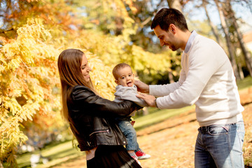 Naklejka na ściany i meble Happy family with baby boy in autumn park