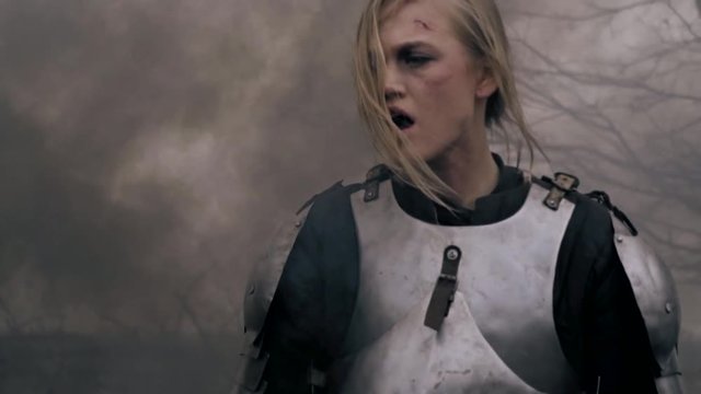 Wounded woman warrior in medieval armor wanders through the smoke