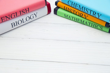 Obraz premium Education concept: school books on different subjects in bright covers on a white wooden table, space for a text or product display