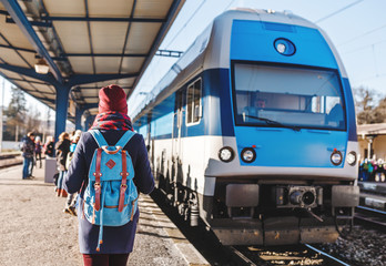 A young tourist girl with backpack waits train on railway station
