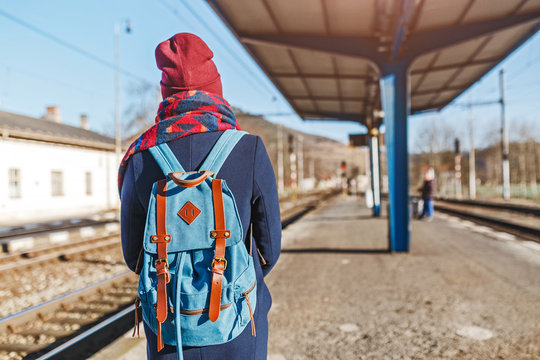 A young tourist girl with backpack waits train on railway station