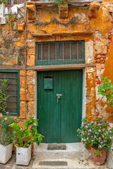 Fototapeta na wymiar Old wall with green locked door and flowers