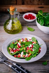 Fresh green salad with spinach, walnuts, goat cheese and pomegranate