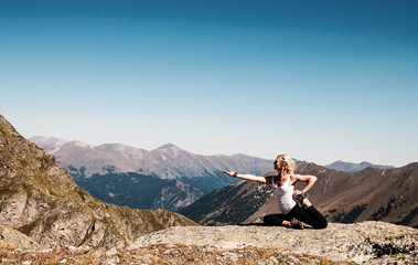 Fototapeta na wymiar Young woman doing yoga pose on the mountain