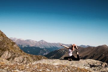 Fototapeta premium Young woman doing yoga pose on the mountain