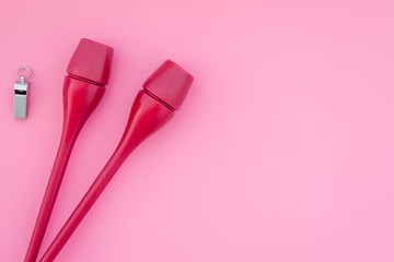 Equipment for rhythmic gymnastics. Clubs on pink background top view copy space