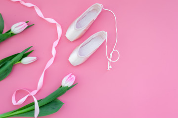 Obraz na płótnie Canvas Ballet pointe shoes near spring tulips on pink background top view copy space