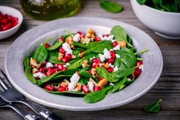 Fresh green salad with spinach, walnuts, feta cheese and pomegranate