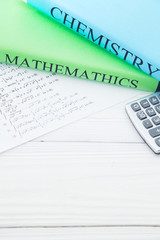 Education concept. Studying exact sciences. Chemistry and Mathematics student's books and tasks on a white wooden table