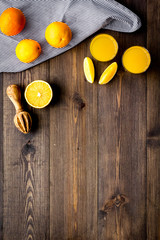 Squeeze juice from oranges. Juicer and slices of oranges on dark wooden background top view copy space