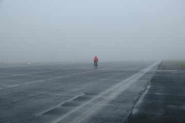 cyclist on empty and foggy road