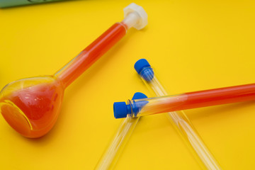 Education concept: Experiments with chemical flasks and test tubes with red and blue liquid on a bright yellow background with copy space