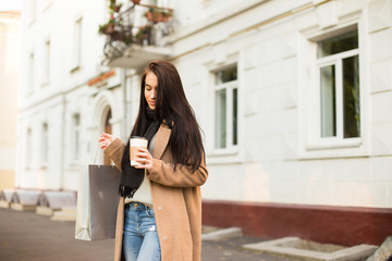 Wooman walking with shopping bag and hot coffee in city center