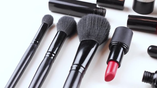 Makeup set of cosmetics with brushes, powder and lipstick is isolated on a white surface.