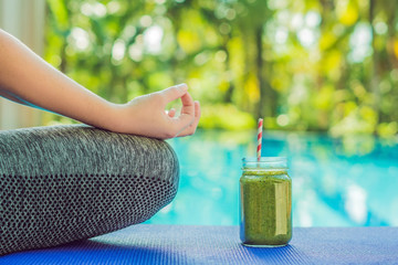 Closeup of a woman's hands during meditation with a green smoothies of spinach, orange and banana...