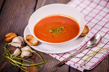 tomato soup  with pasta and chives and bread crouton in white plate on wood table 