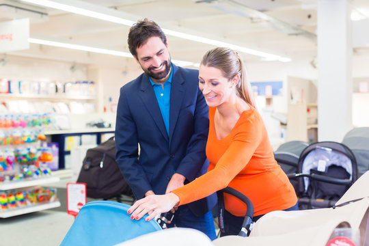 Couple In Baby Shop Buying Stroller, The Woman In Pregnant