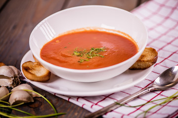 tomato soup  with pasta and chives and bread crouton in white plate on wood table 
