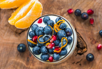 Orange and blueberry yoghurt porridge garnished with friesh fruit. Healty breakfast idea.