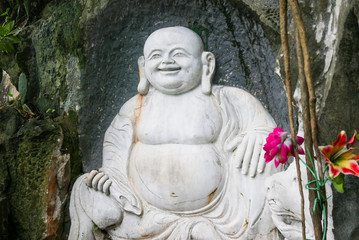 Large carved Buddha with flowers on the side of a mountain in Vietnam